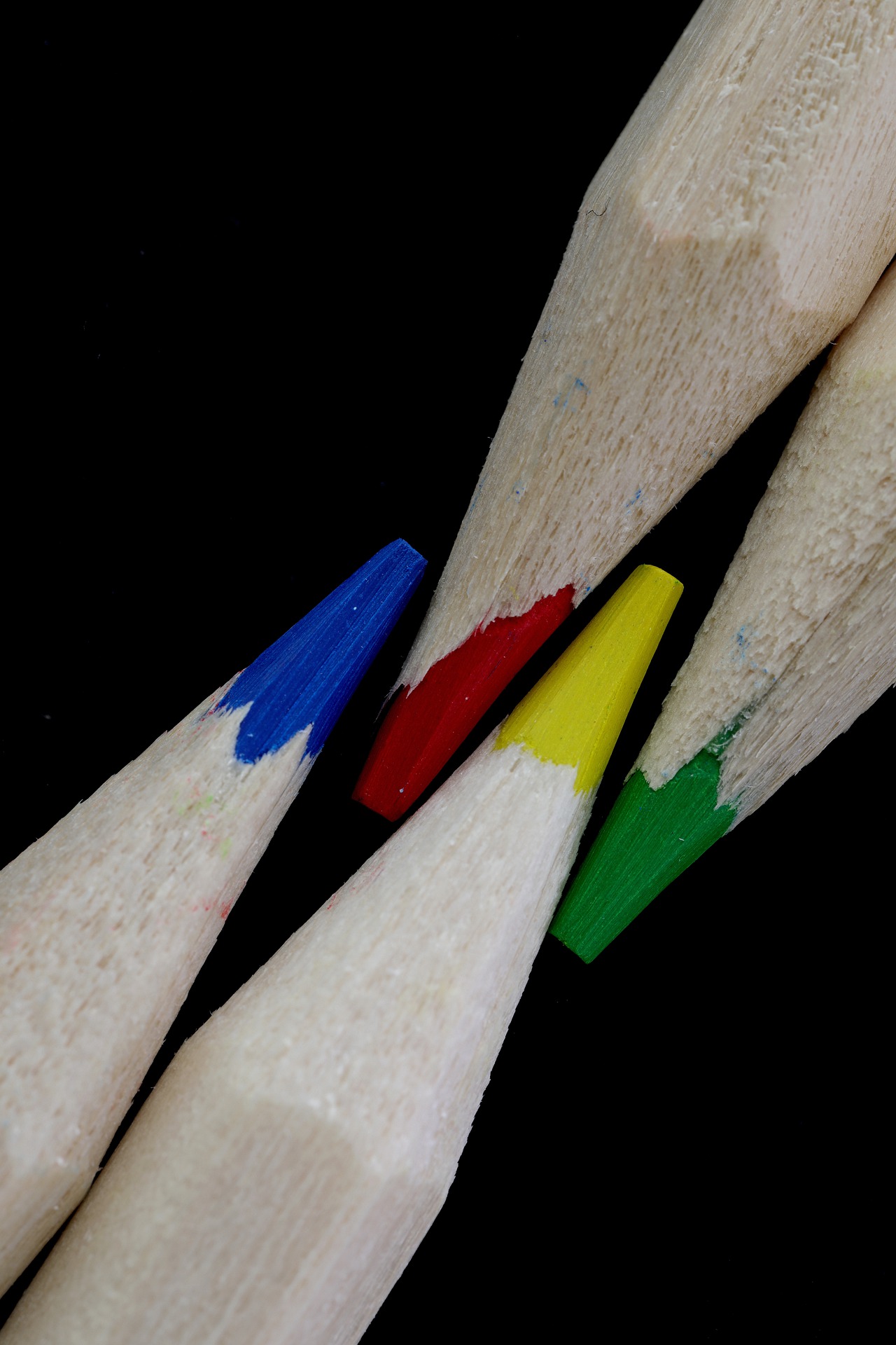 4 Buntstifte in den Farben blau, rot, gelb und blau, die nebeneinander liegen.